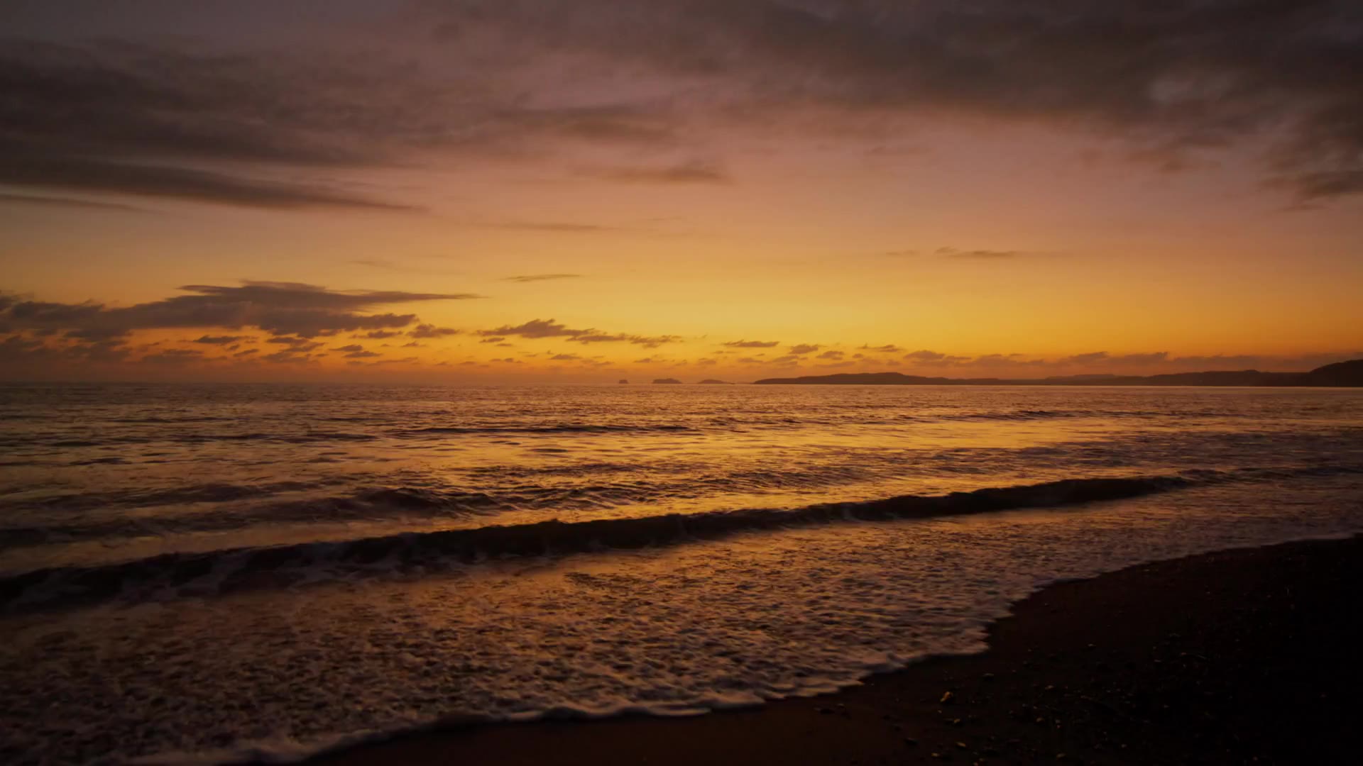 Zonsondergang boven zee, golven die over het strand uitlopen